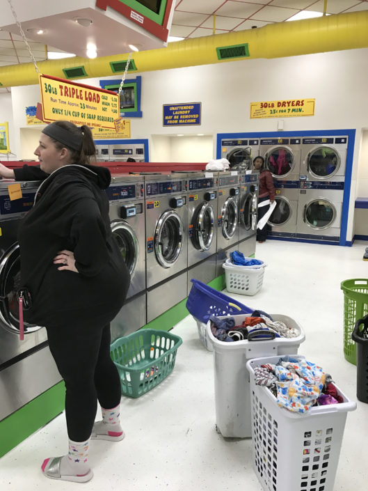 Loads of laundry in bins at Laundry Love QC event at Laundromania in Davenport, Iowa