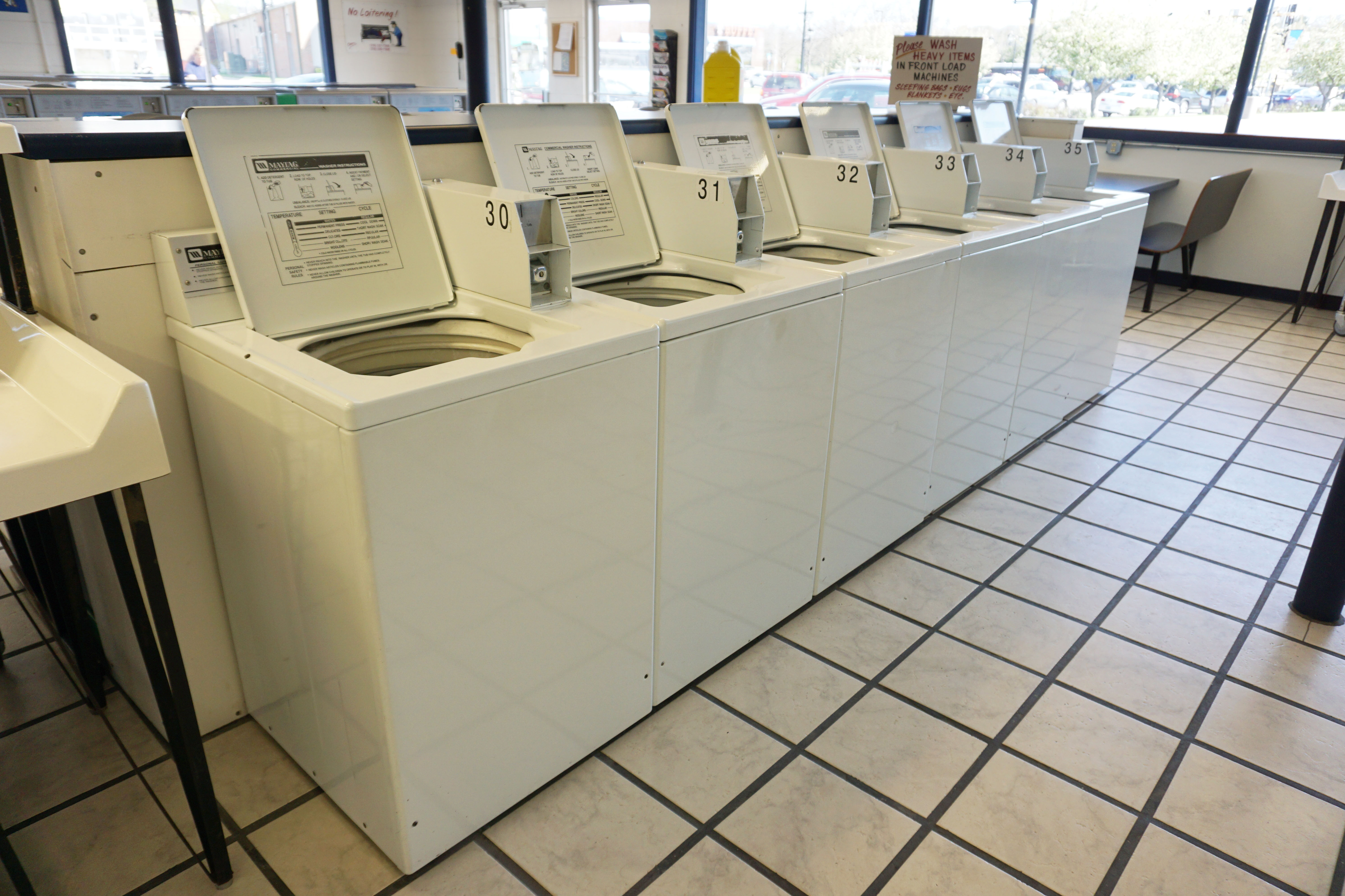 Row of 18lb top load washing machines inside Laundromania Coralville 24